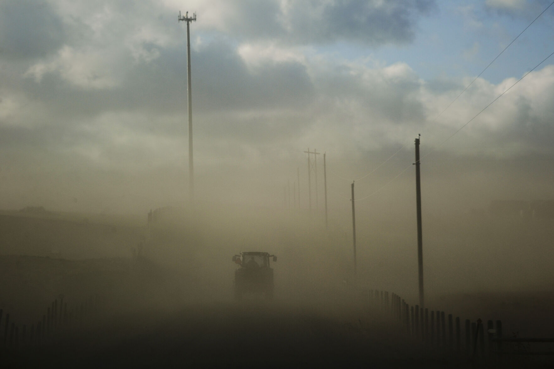 A rancher hauls hay amid a dust storm caused by high winds and no snow cover Tuesday outside Helena, Mont.